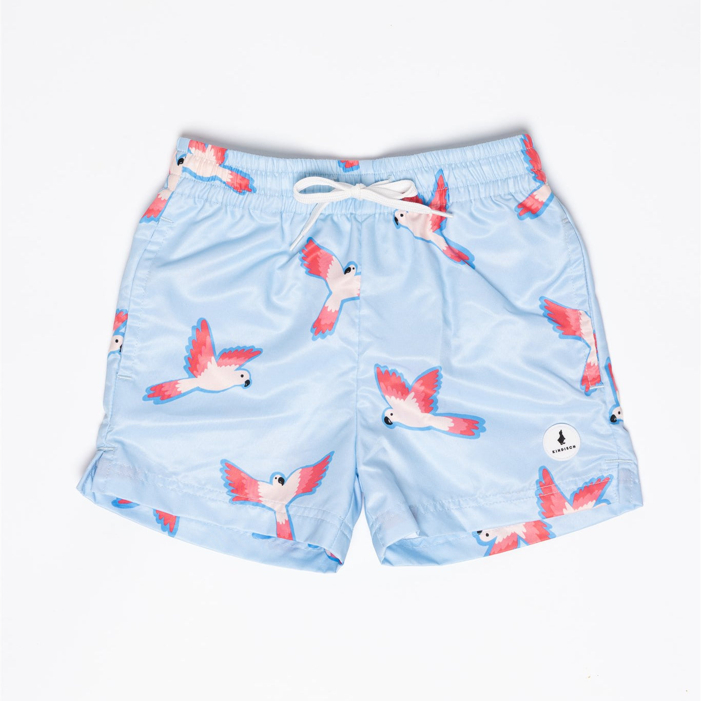 Die Badehose - PARROT für Jungs von KINDISCH ist aus recyceltem Polyester, hellblau mit pink-weißen fliegenden Papageien, weißem Kordelzug und schnelltrocknend – präsentiert auf weißem Hintergrund.