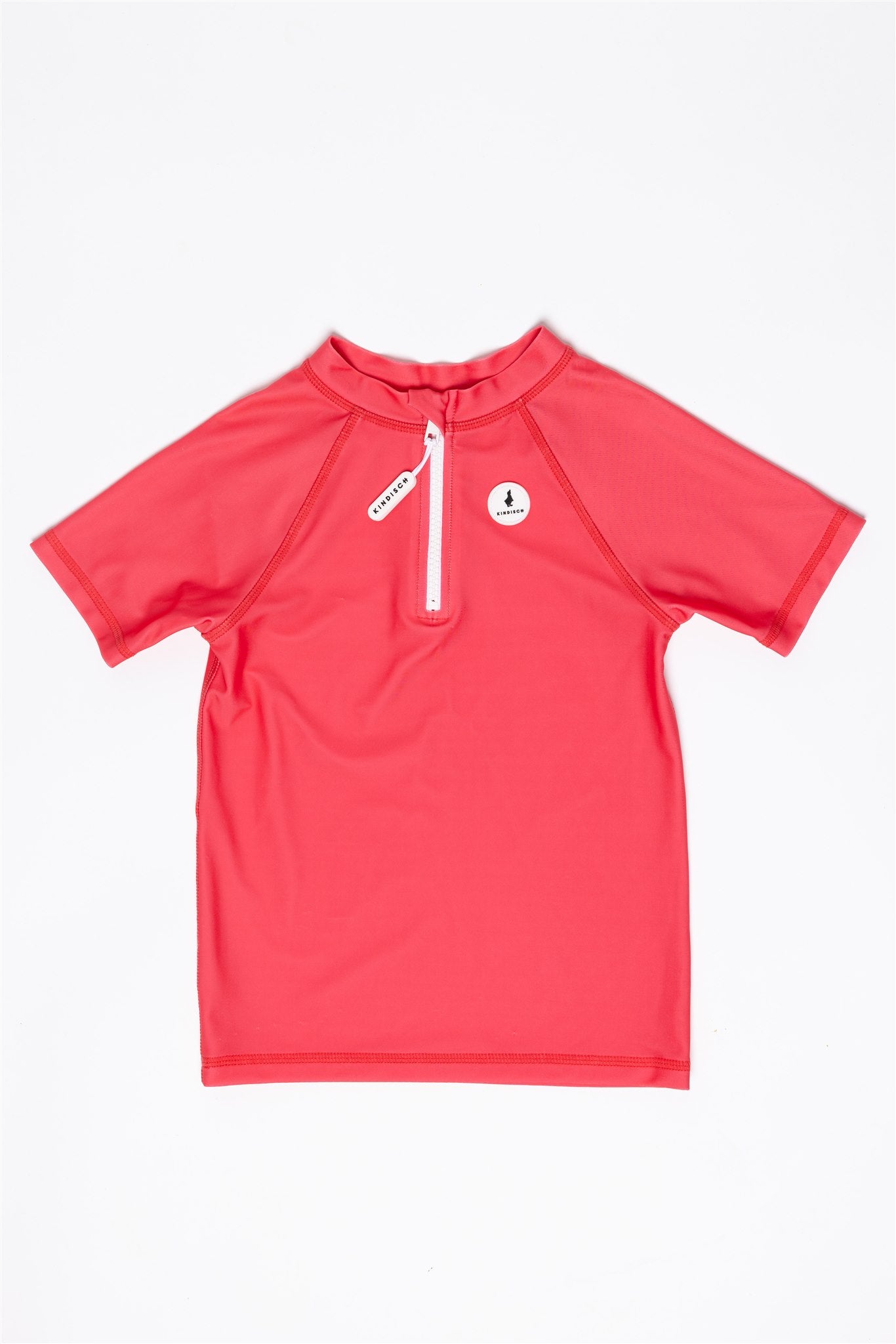 The UV-Shirt kurzarm - Paradise Red by kindischworld.com is a short-sleeve coral red swim shirt with a white front zipper and small round logo on the left chest, offering sun protection and shown laid flat on a white background.