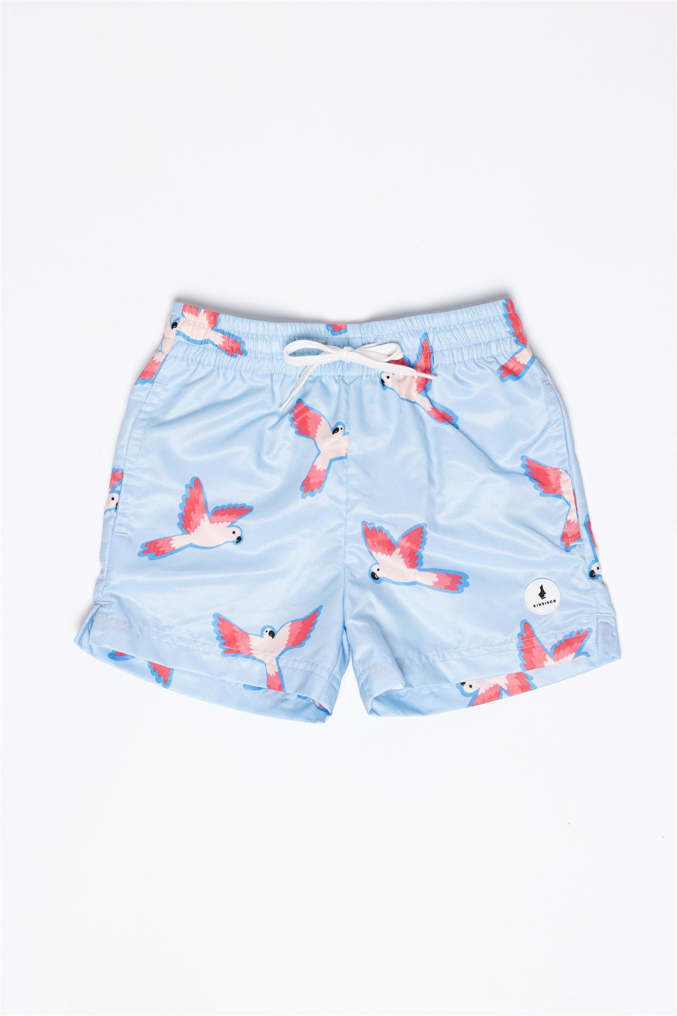 Die Badehose - PARROT für Jungs von KINDISCH ist aus recyceltem Polyester, hellblau mit pink-weißen fliegenden Papageien, weißem Kordelzug und schnelltrocknend – präsentiert auf weißem Hintergrund.
