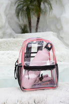 The KINDISCH Kids Backpack – Pink from kindischworld.com, filled with Badesachen such as a pink water bottle, rests by a bright pool, with palm trees and white rocks in the background.