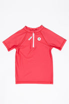 The UV-Shirt kurzarm - Paradise Red by kindischworld.com is a short-sleeve coral red swim shirt with a white front zipper and small round logo on the left chest, offering sun protection and shown laid flat on a white background.